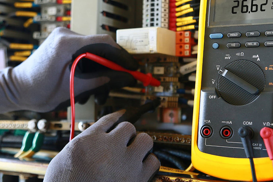 des mains gantées avec un testeur électrique