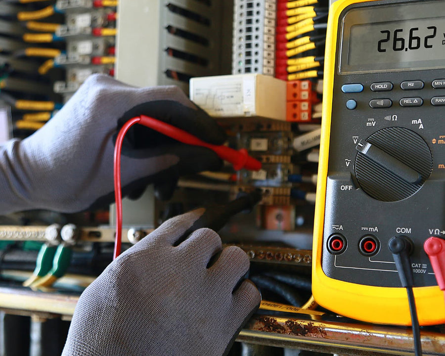 des mains gantées avec un testeur électrique