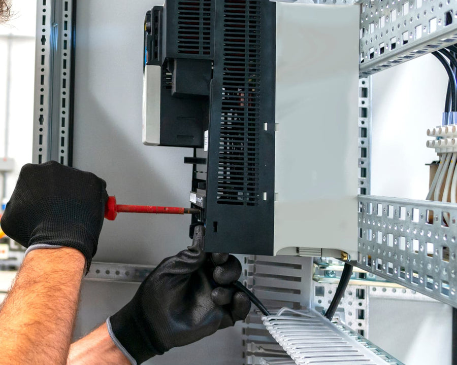 Mains gantées avec un tournevis sur une arrivée électrique
