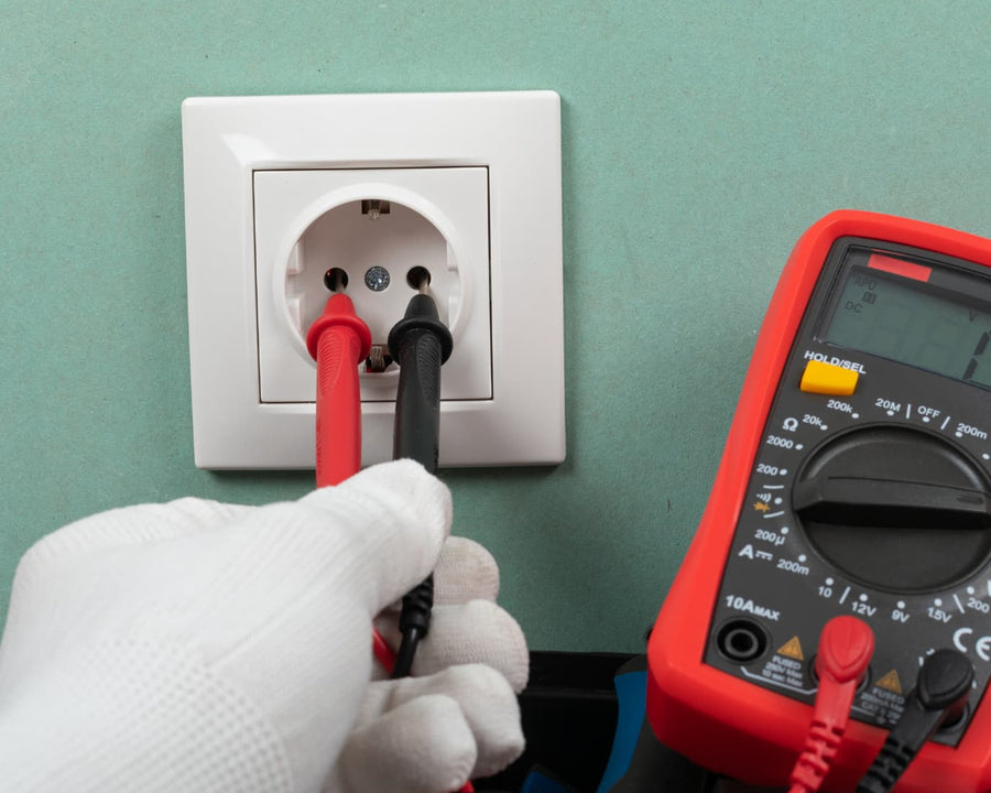 Une prise avec une main gantée et un testeur électrique