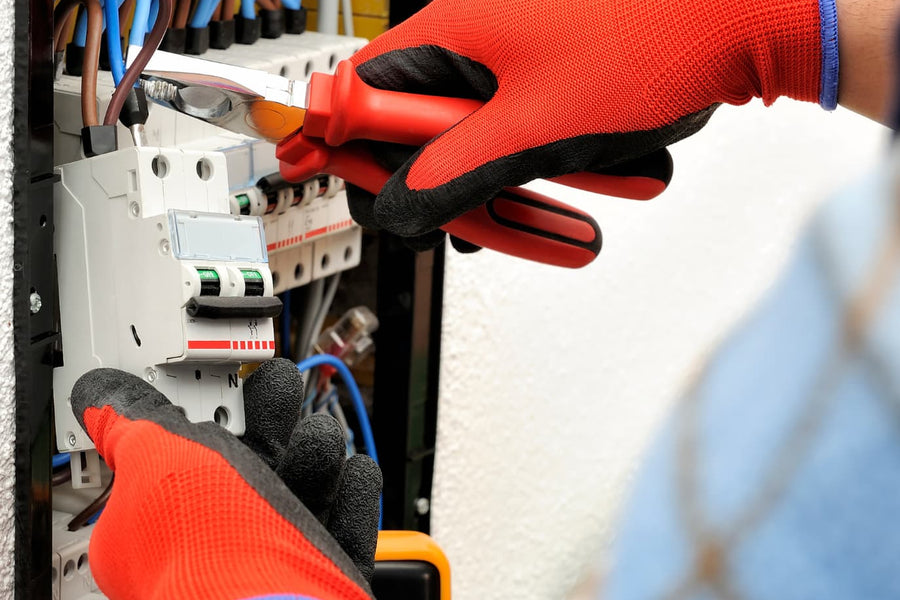 mains gantées avec une pince disjoncteur électrique